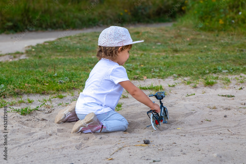 adorable toddler plays with a toy bike in nature. child on all fours in the sand on the lawn adorable toddler plays with a toy bike in nature. child on all fours in the sand on the lawn