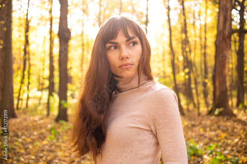 portrait of young beautiful woman in autumn park in sun shines. thinkfull young woman © Maria