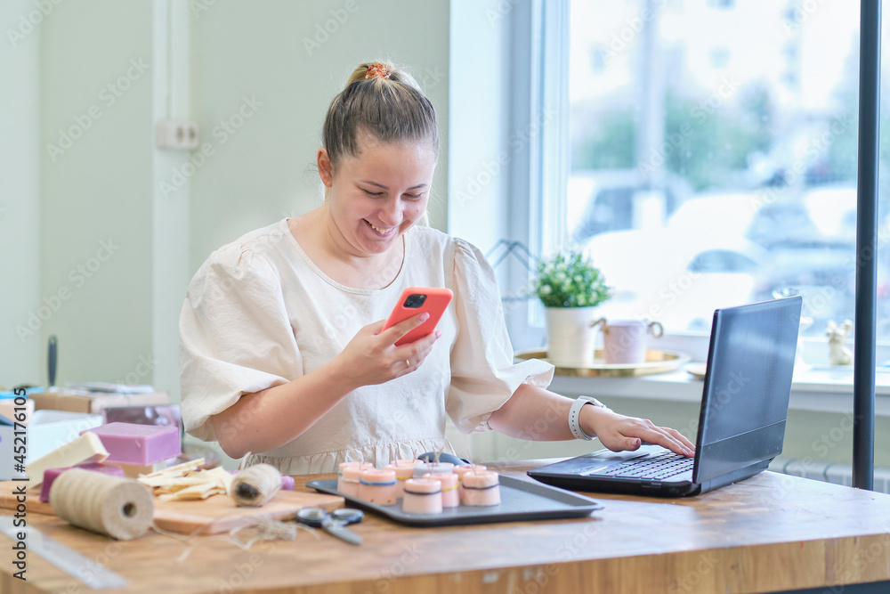 Small business owner. Portrait of mature woman standing at her shop behind the laptop and smiling. female online store seller entrepreneur packing package post shipping box preparing delivery parcel. Small business owner. Portrait of mature woman standing at her shop behind the laptop and smiling. female online store seller entrepreneur packing package post shipping box preparing delivery parcel.