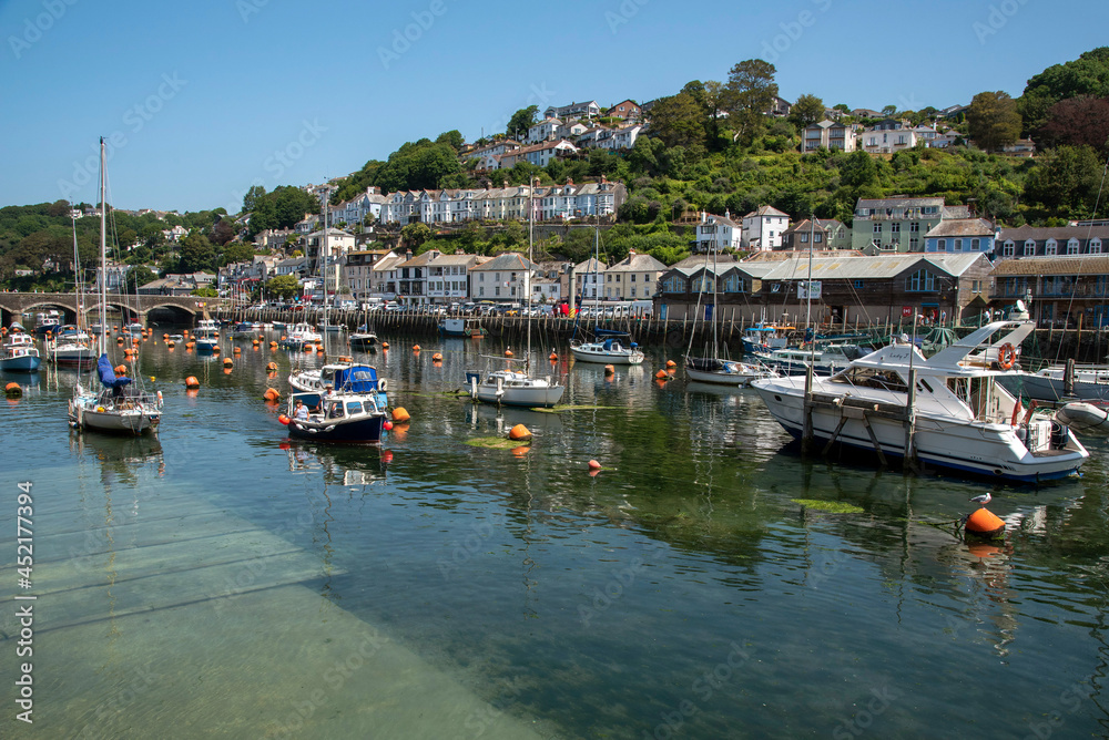 Looe, Cornwall, England, UK. 2021.  Low tide ebb on the River Looe a tidal river showing a submerged slipway and many boats looking to East Looe, Cornwall.