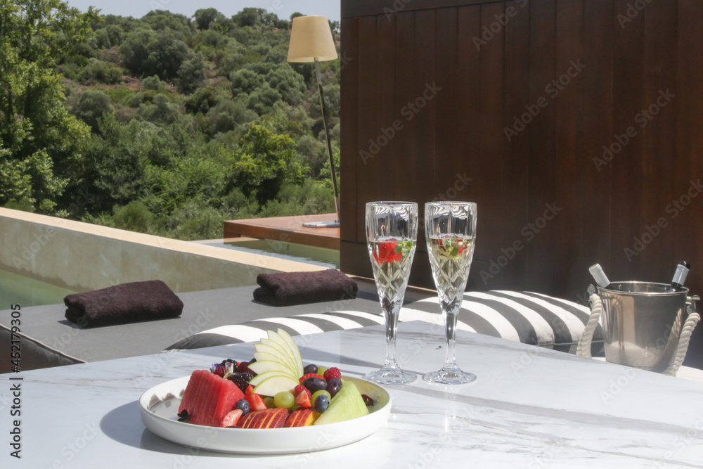 Champagne in crystal glasses and fruit salad served on the balcony table