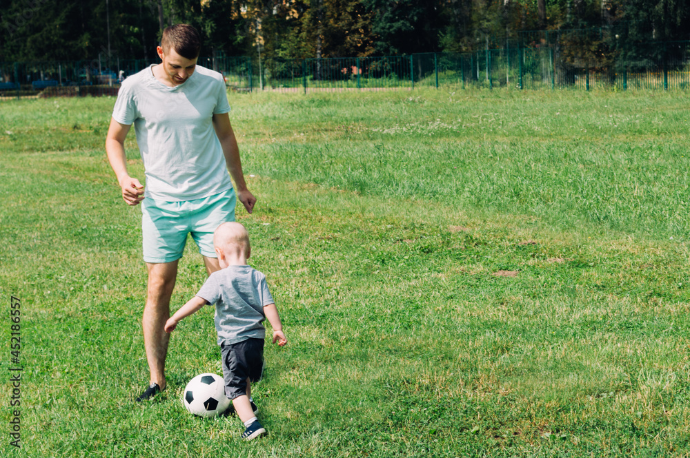 Son and father playing soccer on the grass in summer Son and father playing soccer on the grass in summer
