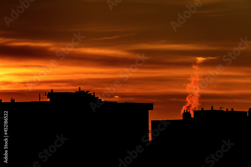 Dark smoke from pipes in the air at sunset. Two large pipes of industrial factory produce chemical smoke in the evening. Environmental pollution.