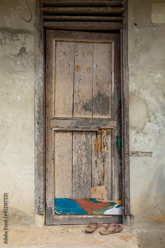 Flip-flops in front of a weathered wooden door in a humble little house, in the town of Friwin, Raja Ampat, West Papua, Indonesia photo