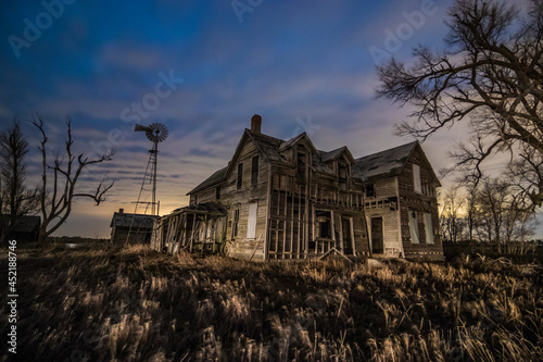 An abandoned house with a windwill at night photo