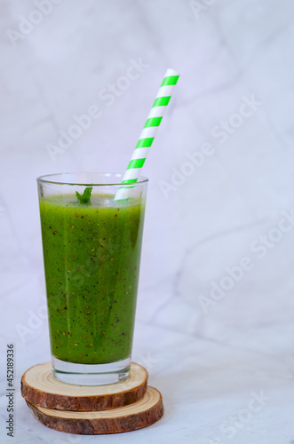 Top view of fresh green healthy smoothie in a glass made of kiwi, chia seeds and banana with mint. Creative concept of healthy detox drink, diet or vegetarian food concept. Copy space.