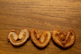 top view of many delicious freshly baked puff pastry ears on a wood colored board