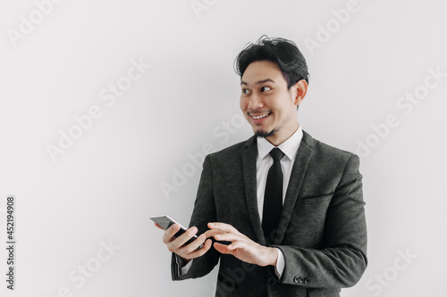 Happy smile face of Asian businessman use smartphone in concept of trading app. © Sevendeman