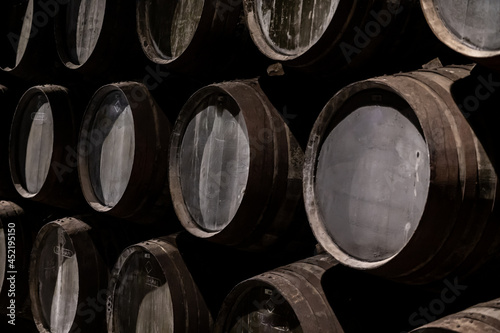 Old porto lodge with rows of oak wooden casks for slow aging of fortified ruby or tawny porto wine in Vila Nova de Gaia, Portugal