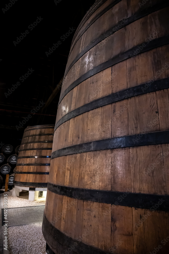 Old porto lodge with rows of oak wooden casks for slow aging of fortified ruby or tawny porto wine in Vila Nova de Gaia, Portugal Old porto lodge with rows of oak wooden casks for slow aging of fortified ruby or tawny porto wine in Vila Nova de Gaia, Portugal