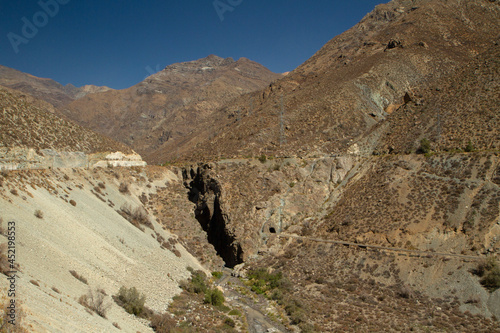 The Andes mountains in summer. View of river flowing across the rocky canyon and the train railway into the mountains.