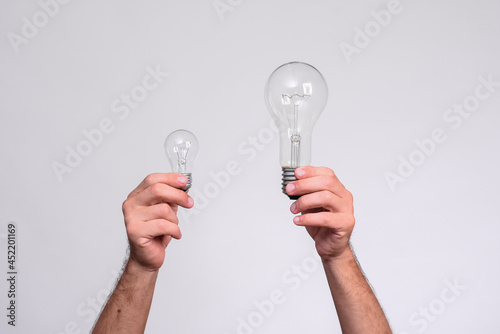 two light bulbs in men's hands. large and small incandescent lamps. on a white background.