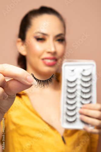 chica sosteniendo pestaña postiza con fondo desenfocado. photo