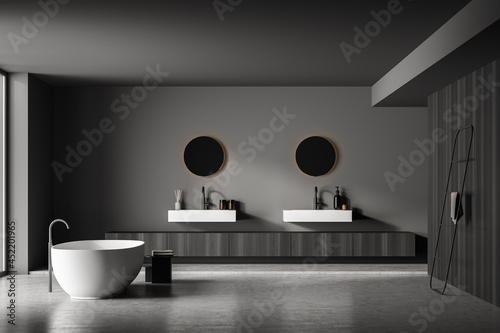 Dark bathroom interior with bathtub  panoramic window  carpet  concrete floor