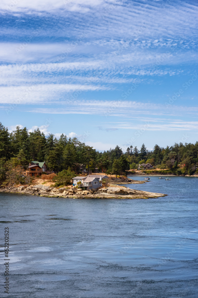 Panoramic View of a Cosy Homes on the rocky coast during a sunny summer day. Taken on Galiano Island near Vancouver Island, BC, Canada.