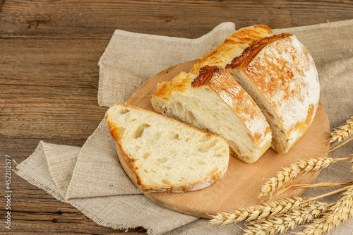 Freshly baked bread with wheat ears, fragrant pieces on a cutting board