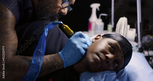 Tattoo artist working with client