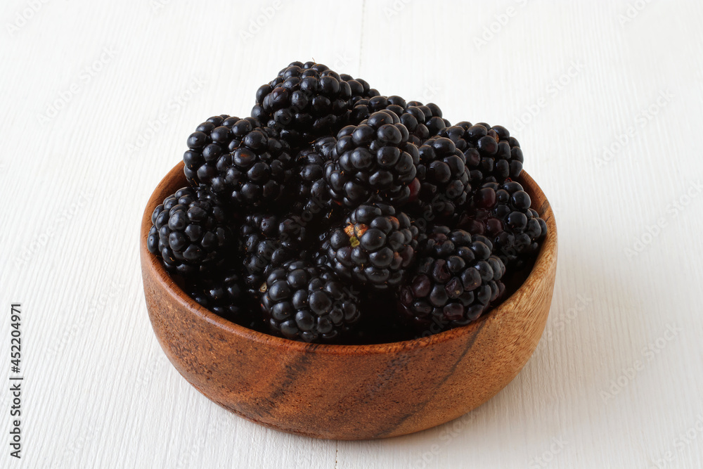Ripe blackberries, wooden bowl with fresh blackberries from local farmers market, high angle view on white wooden table. Ripe blackberries, wooden bowl with fresh blackberries from local farmers market, high angle view on white wooden table.