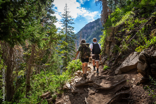 Two teen boys hiking together with backpacks up a rugged mountain trail