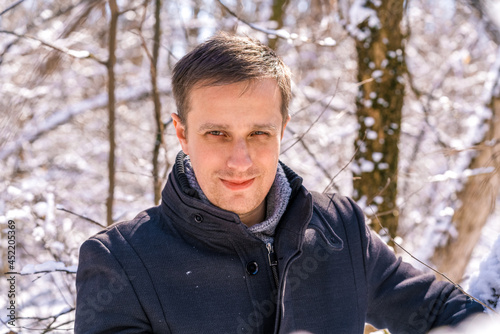 Handsome smiling bearded man in black coat in winter day