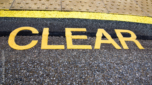 A loudly written yellow sign on a platform to CLEAR people away from the edge and in a safe area. photo