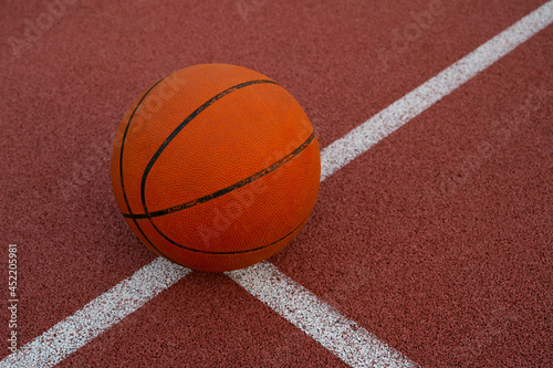 Basketball ball placed on urban street (outdoor) basketball court.