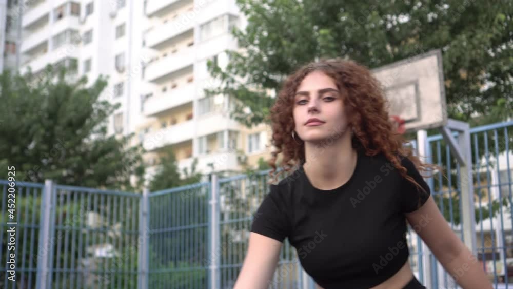Young beautiful sportive woman playing street basketball on the court outdoors Young beautiful sportive woman playing street basketball on the court outdoors
