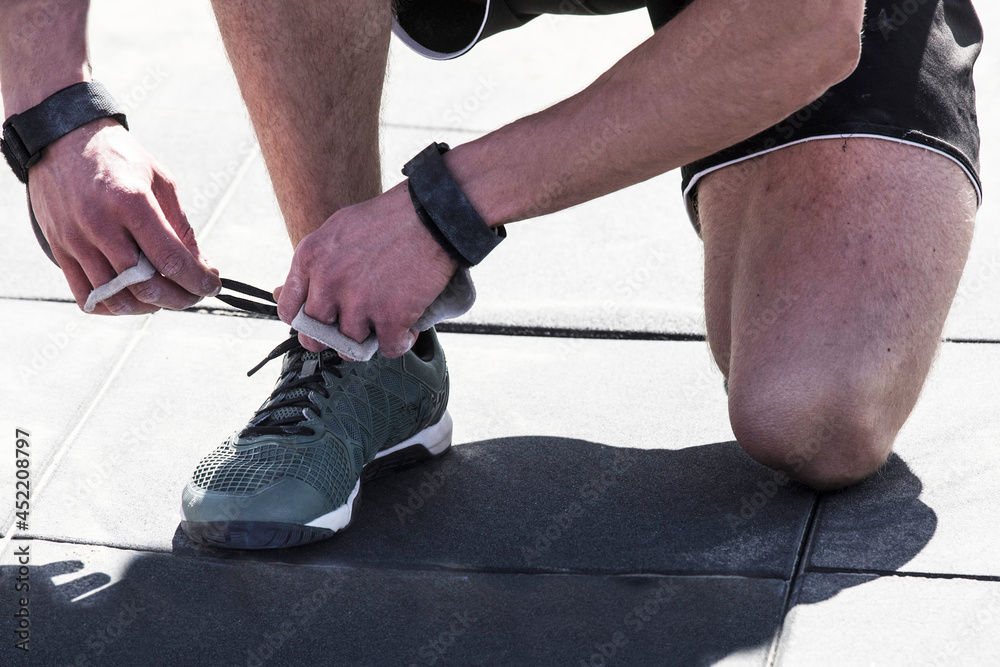 outdoor fitness competition,   man an athlete ties a shoelace