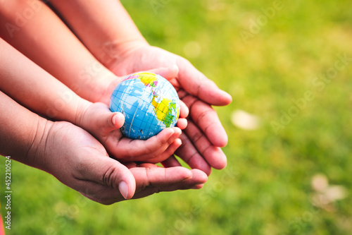 Fototapeta Naklejka Na Ścianę i Meble -  Eco Friendly Concept. The hands of children and adults are holding the world safe from global warming. Caring for our world. World Environment day.