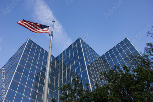 A low angle shot of a reflective city office building exterior with the American flag flying outside