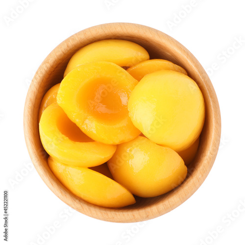 Halves of canned peaches in wooden bowl isolated on white, top view