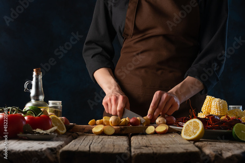 The chef is cutting potatoes on a cutting board. He cooks corn with crayfish and vegetables. Step by step recipe. Restaurant, cafe, hotel, advertising, menu design.