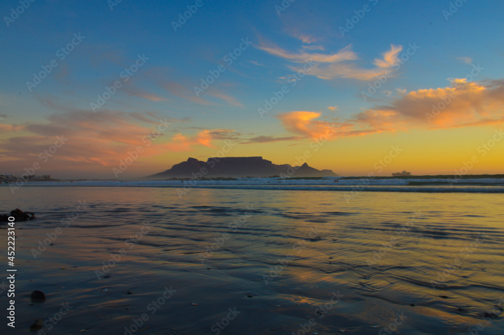 Dramatic sky at sunset beach in Bloubergstrand cape town with table mountain at back drop