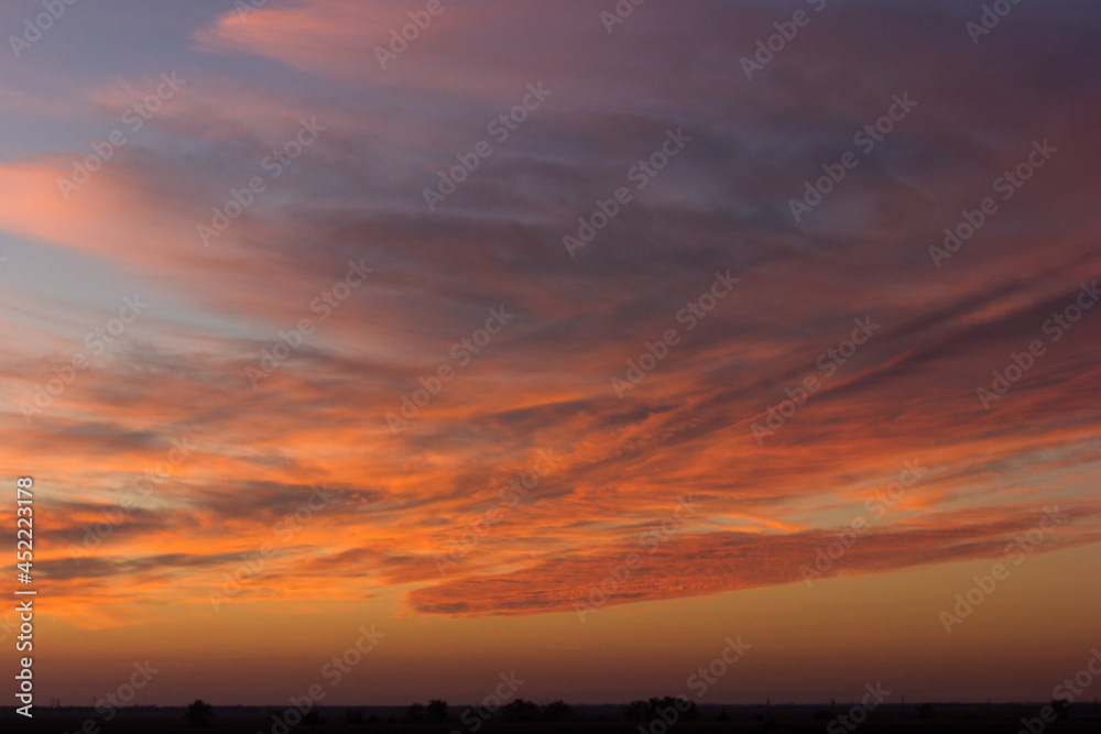 A wide shot of a dramatic orange and blue sunset or sunrise sky