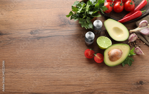 Fresh guacamole ingredients on wooden table, flat lay. Space for text