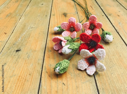 Crochet colorful “Combretum indicum “ flowers on the wooden in handmade concept
