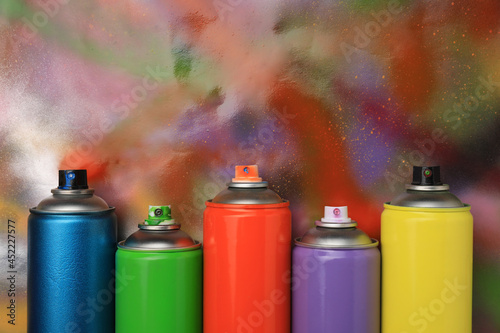 Cans of different graffiti spray paints on color background, flat lay. Space for text