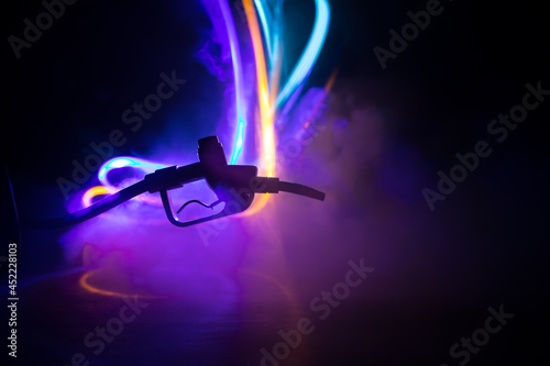 Creative concept. Silhouette of gasoline pistol miniature on dark toned foggy background. Close up. Industrial decorated elements on background.