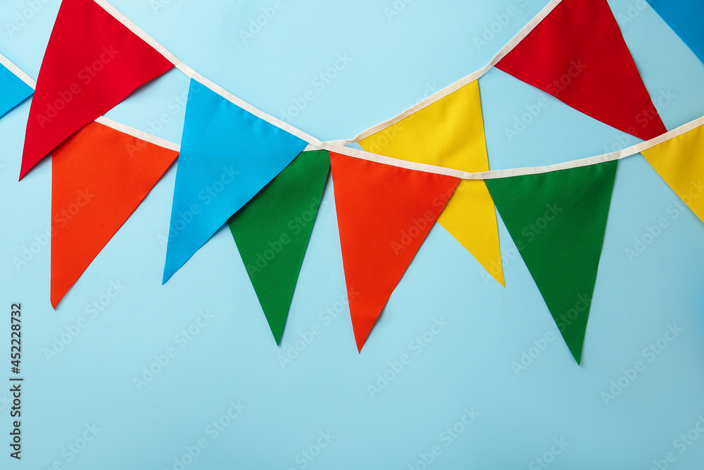 Buntings with colorful triangular flags on light blue background. Festive decor