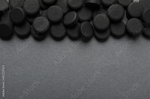 Activated charcoal pills on grey background, flat lay with space for text. Potent sorbent photo