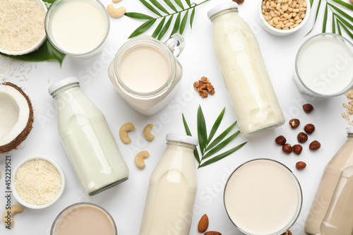 Different vegan milks and ingredients on white background  flat lay