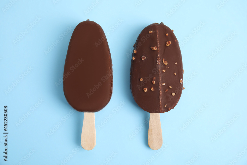 Ice cream bars glazed in chocolate on light blue background, flat lay Ice cream bars glazed in chocolate on light blue background, flat lay
