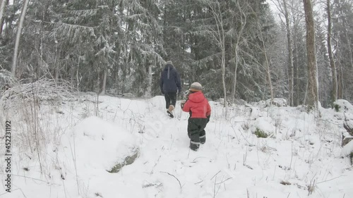 SLOW MOTION, a parent and child walk through a snowy forest photo