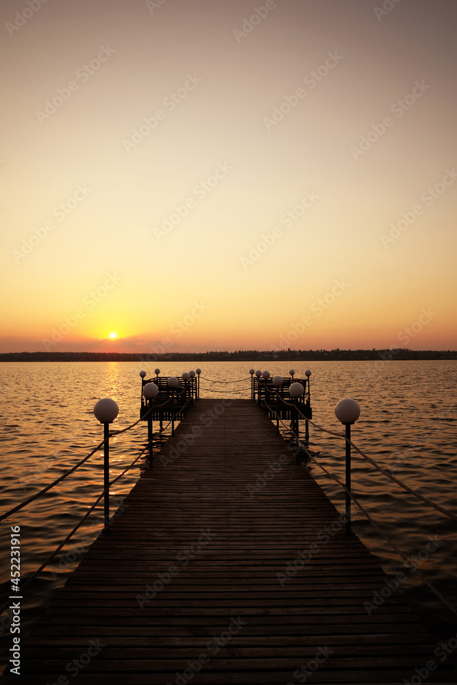 Picturesque view of empty wooden pier with lanterns at sunset