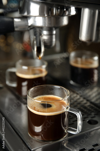 Making fresh aromatic espresso using professional coffee machine