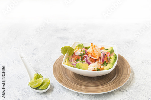 shrimp ceviche dish with avocado, tomato and onion on a light background photo