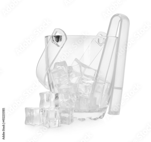 Glass bucket with ice cubes and tongs on white background