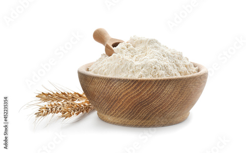Flour in bowl and spikelets on white background