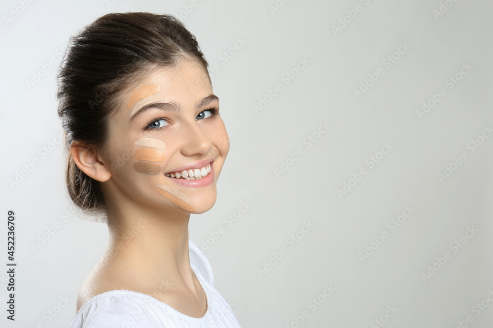 Beautiful girl on light grey background. Using concealers and foundation for face contouring Beautiful girl on light grey background. Using concealers and foundation for face contouring