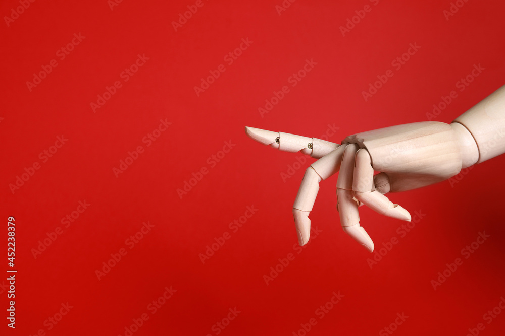 Wooden mannequin hand on red background. Space for text Wooden mannequin hand on red background. Space for text